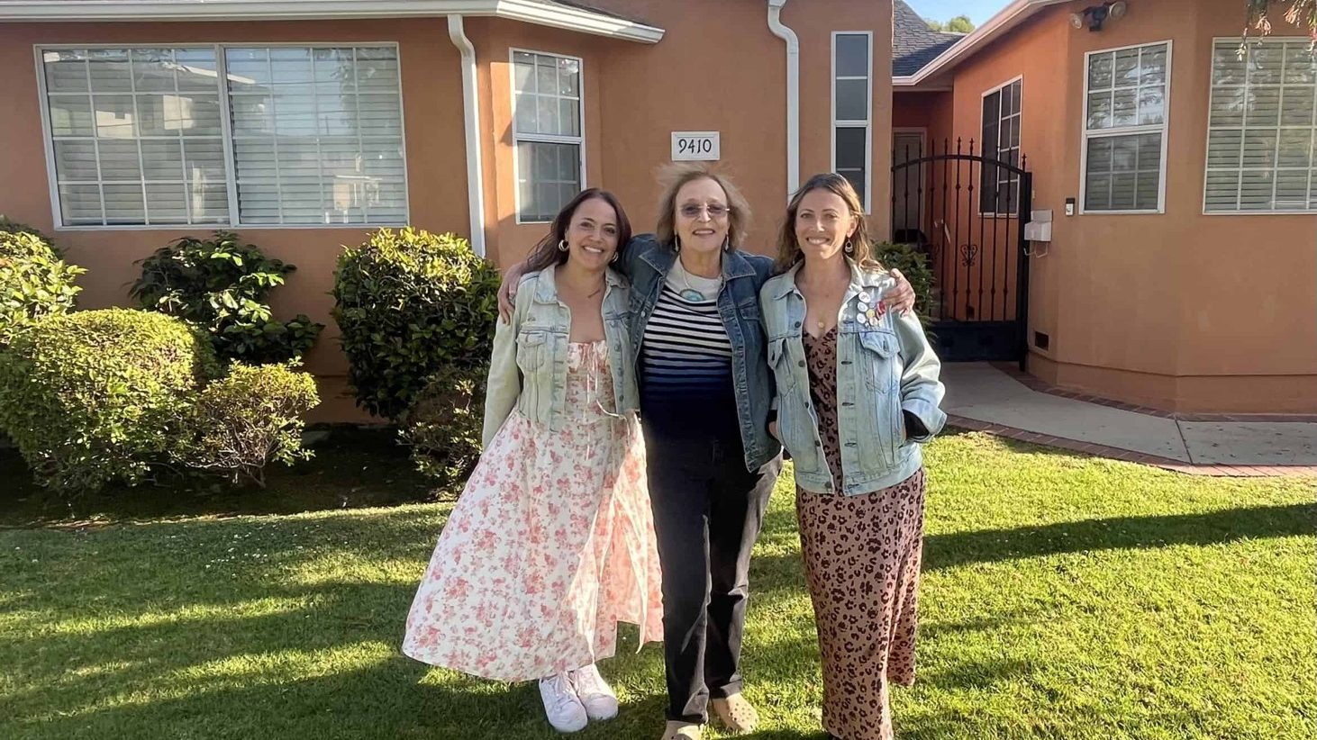 Three women standing on the lawn in front of a house