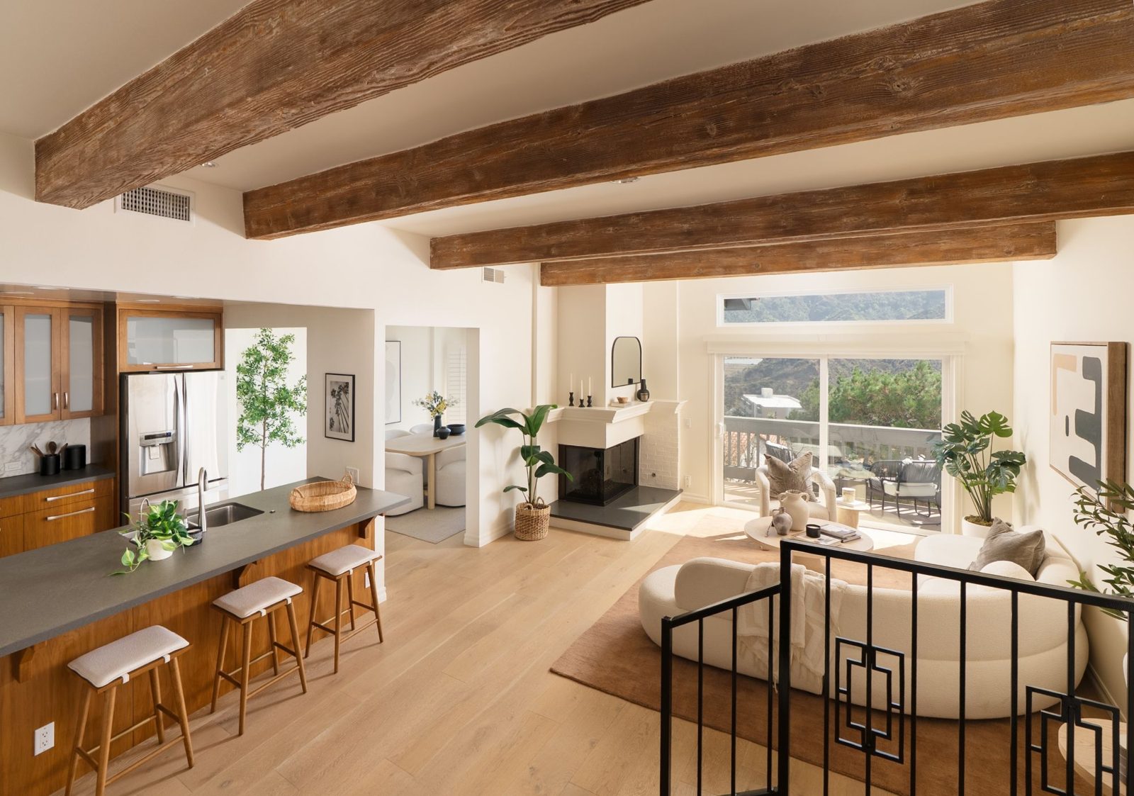 Open living and kitchen area with wood beams and a corner fireplace